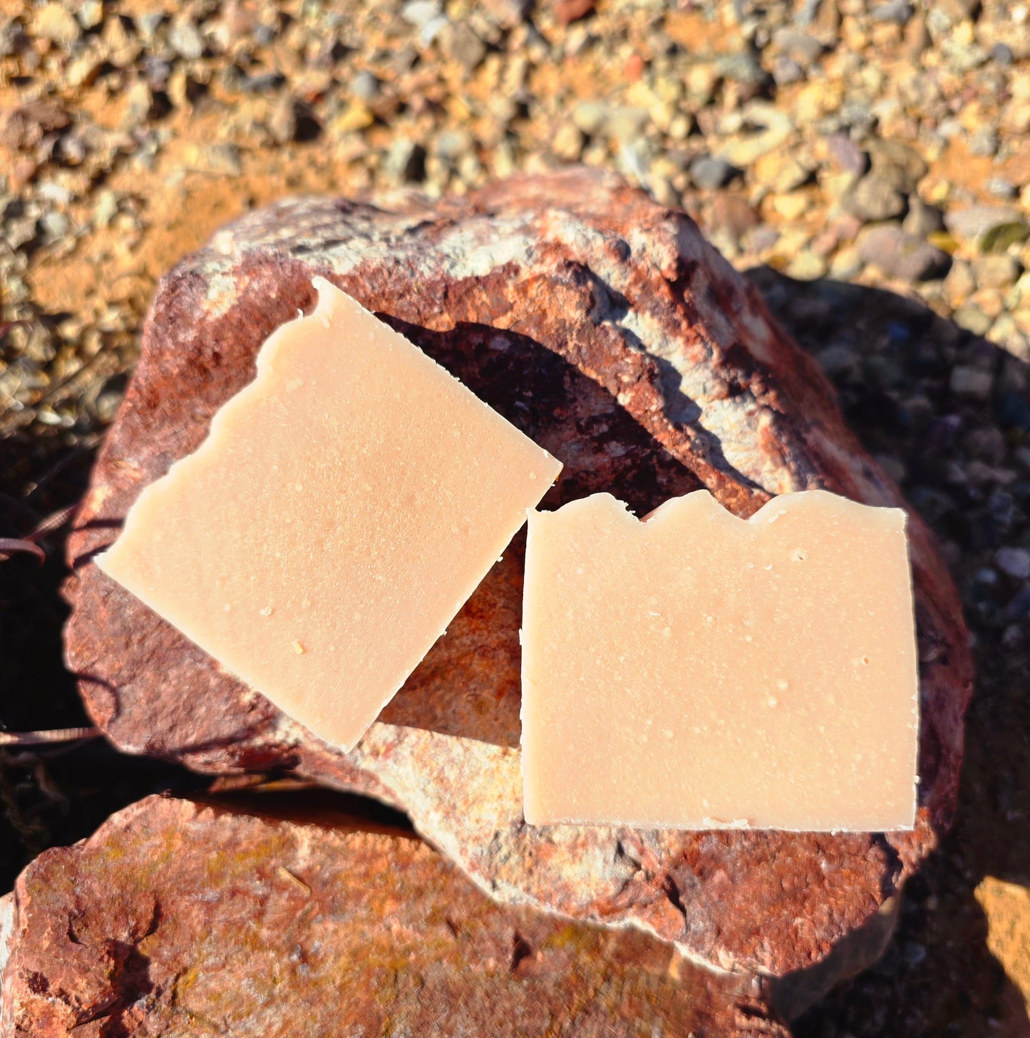 Two unwrapped bars of Herban Desert's all natural lavender goat milk soap. With a creamy, slightly pink color.