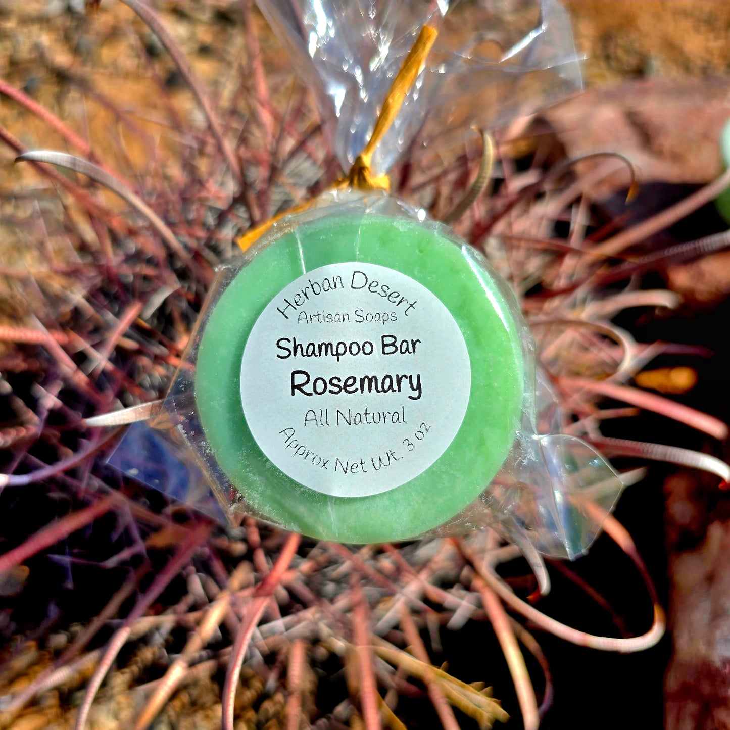 A green shampoo bar with rosemary essential oil from Herban Desert, wrapped in clear packaging with a ribbon.