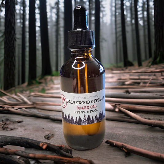 Bottle of Herban Desert's Olivewood Cypress beard oil with a forest background.